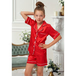 Load image into Gallery viewer, Kids red satin pyjamas. Button up shirt with your personalised name above the pocket with matching shorts. Body colour red with a white contrast piping and buttons. Personalised for you!