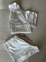 Load image into Gallery viewer, Ladies long satin pyjamas in Ivory with a Champagne contrast satin piping snd buttons. Short sleeve button shirt with a pocket to the right of the chest and your personalised name above. Shorts with both pockets and an adjustable tie around the waist.