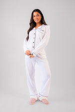 Load image into Gallery viewer, A beautiful set of ladies personalised white jersey pyjamas. Soft and comfortable personalisation above the front pocket on the left chest . Black contrasting trim around the collar alongside the buttons down to the front, also around the ankles and wrist . A nice classy design with your comfort in mind.