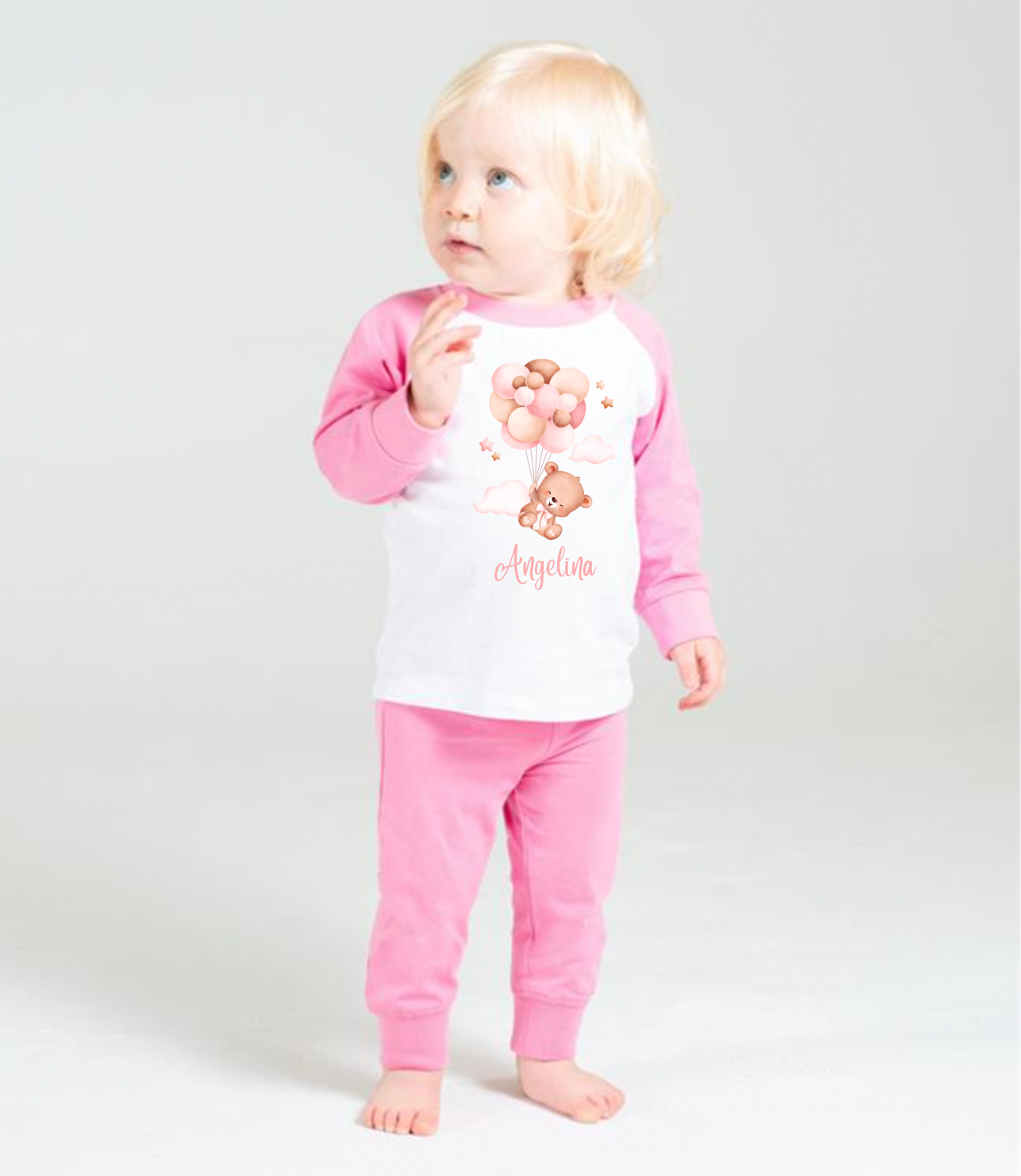 Babies raglan design pyjamas in White and Pink Colour. With a teddy bear design holding pink balloons on the front with a personalised name in pink below. 