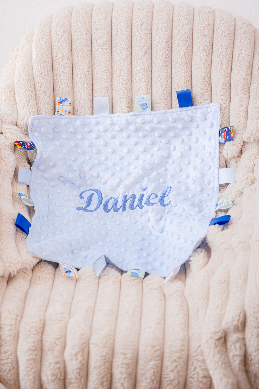 Baby boy blue personalised  soft plush comforter. Personalisation embroidered in the middle in light blue which complements the accent tags around the edges. A nice square soft comforter to help keep the little one content.