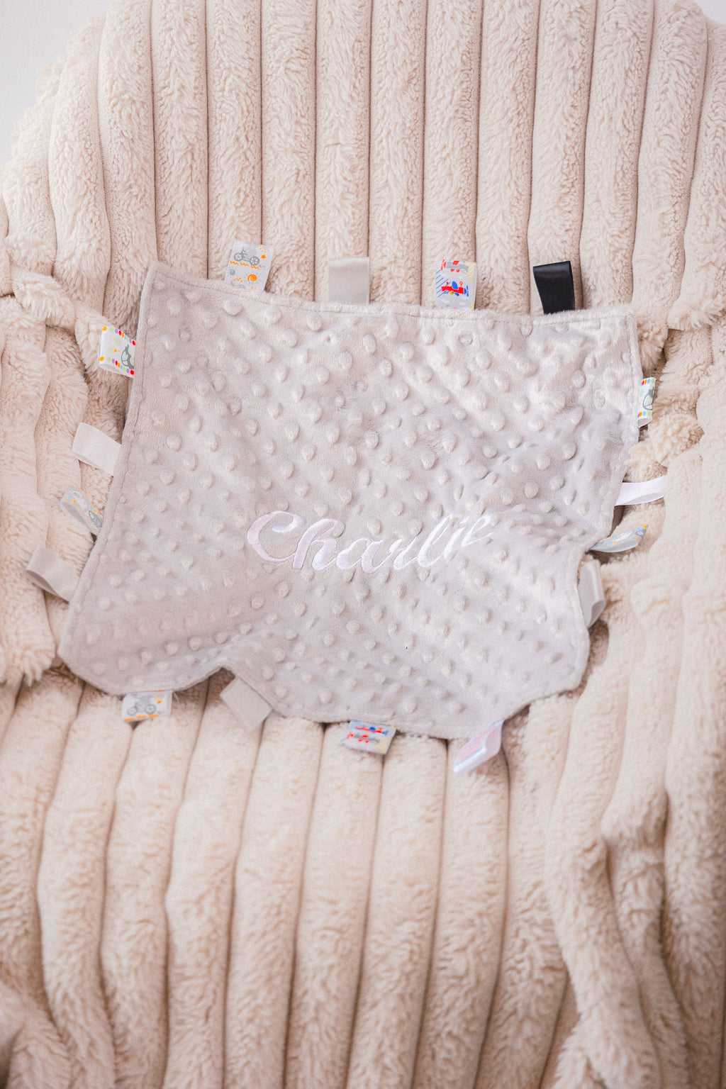 Babies unisex beige personalised soft plush comforter. Personalisation embroidered in the middle in a light beige cotton which complements the accent tags around the edges. A nice square soft comforter to help keep the little one content.
