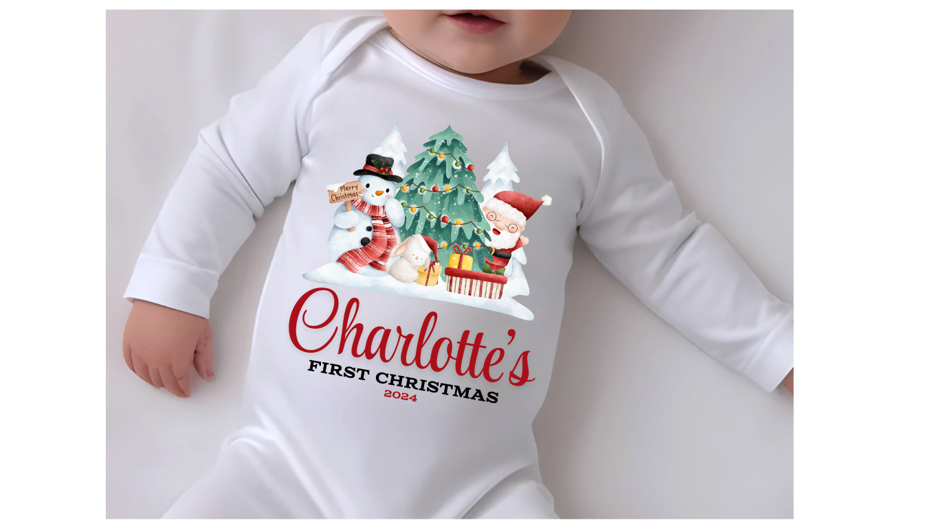 A white personalised unisex soft cotton 
 sleep suit for babies with a Christmas theme print, including a design with Santa Claus, Christmas tree and a snowman. Personalisation to the middle below the design in red print with first Christmas written underneath. A sure way to get a first Christmas photo of your baby. 