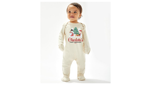 A cream personalised unisex soft cotton 
 sleep suit for babies with a Christmas theme print, including a design with Santa Claus, Christmas tree and a snowman. Personalisation to the middle below the design in red print with first Christmas written underneath. A sure way to get a first Christmas photo of your baby. 
