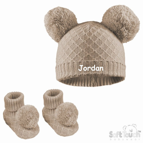 A soft beige, cable knitted baby bootees and a hat with pom-poms, personalised along the front. A lovely set to help keep those little ones warm this winter when venturing outdoors.