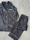 These include a button up shirt with your personalised name above the pocket and trousers, with pockets on either side and an adjustable tie around the waist. The perfect personalised gift for children! Black body colour with a White contrast piping and buttons. Personalised for you! 