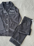 These include a button up shirt with your personalised name above the pocket and trousers, with pockets on either side and an adjustable tie around the waist. The perfect personalised gift for children! Black body colour with a White contrast piping and buttons. Personalised for you! 