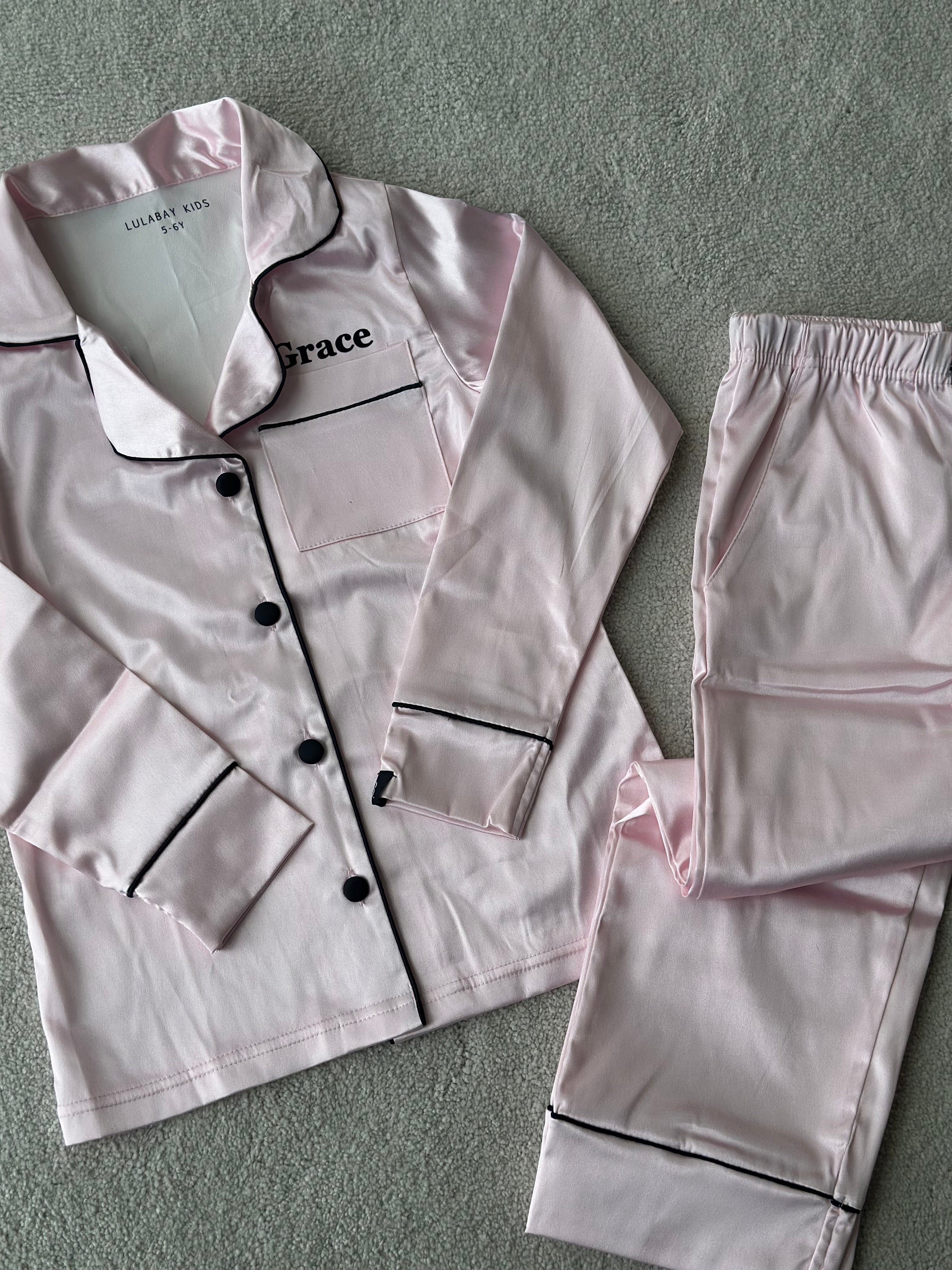 These include a button up shirt with your personalised name above the pocket. Trousers with pockets on either side and an adjustable tie around the waist. The perfect personalised gift for children! Light Pink body colour with a Black contrast piping and buttons. Personalised for you! 