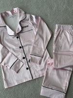 Load image into Gallery viewer, These include a button up shirt with your personalised name above the pocket. Trousers with pockets on either side and an adjustable tie around the waist. The perfect personalised gift for children! Light Pink body colour with a Black contrast piping and buttons. Personalised for you! 
