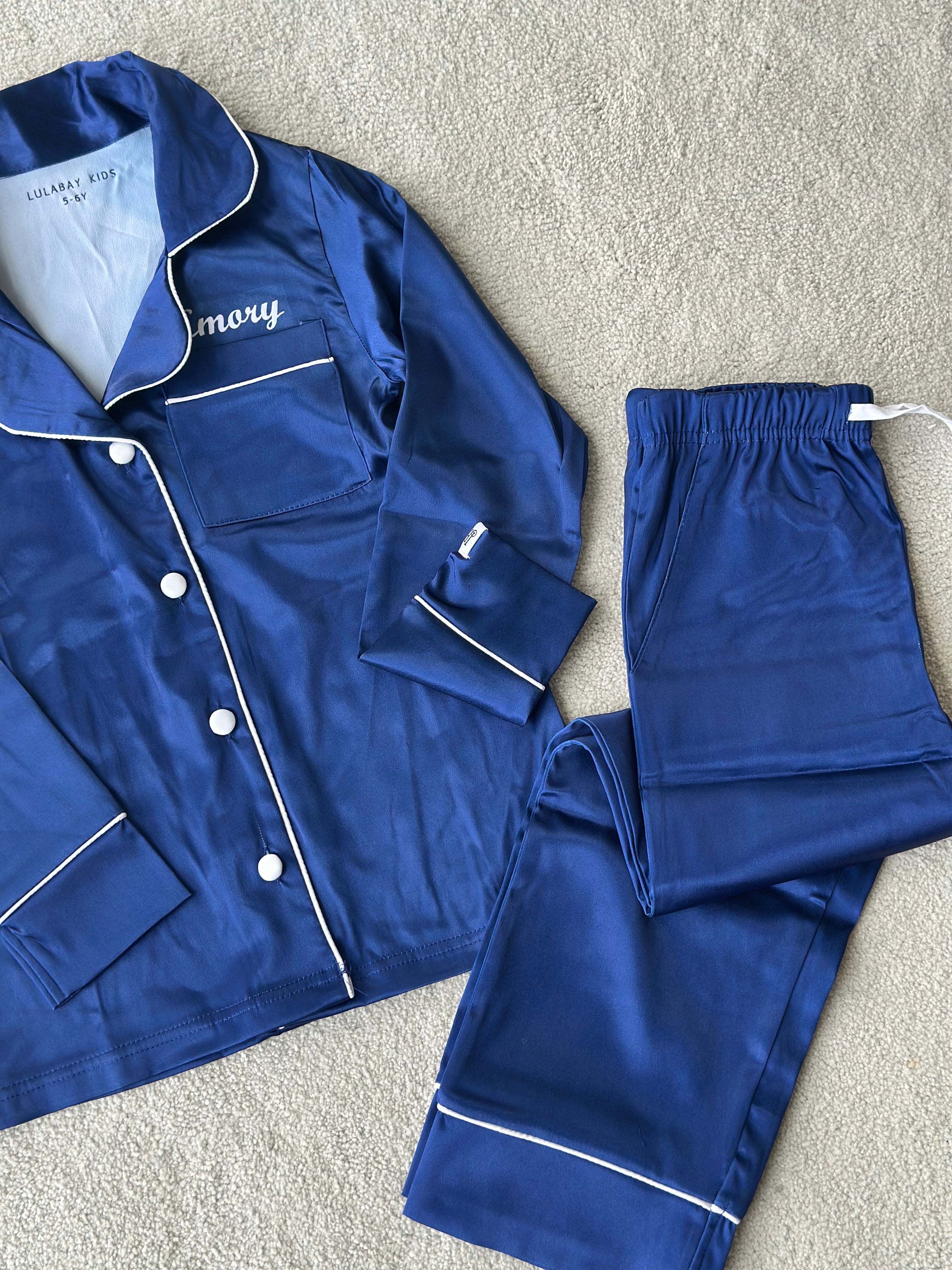 These include a button up shirt with your personalised name above the pocket and trousers, with pockets on either side and an adjustable tie around the waist. The perfect personalised gift for children! Navy body colour with a White contrast piping and buttons. Personalised for you! 