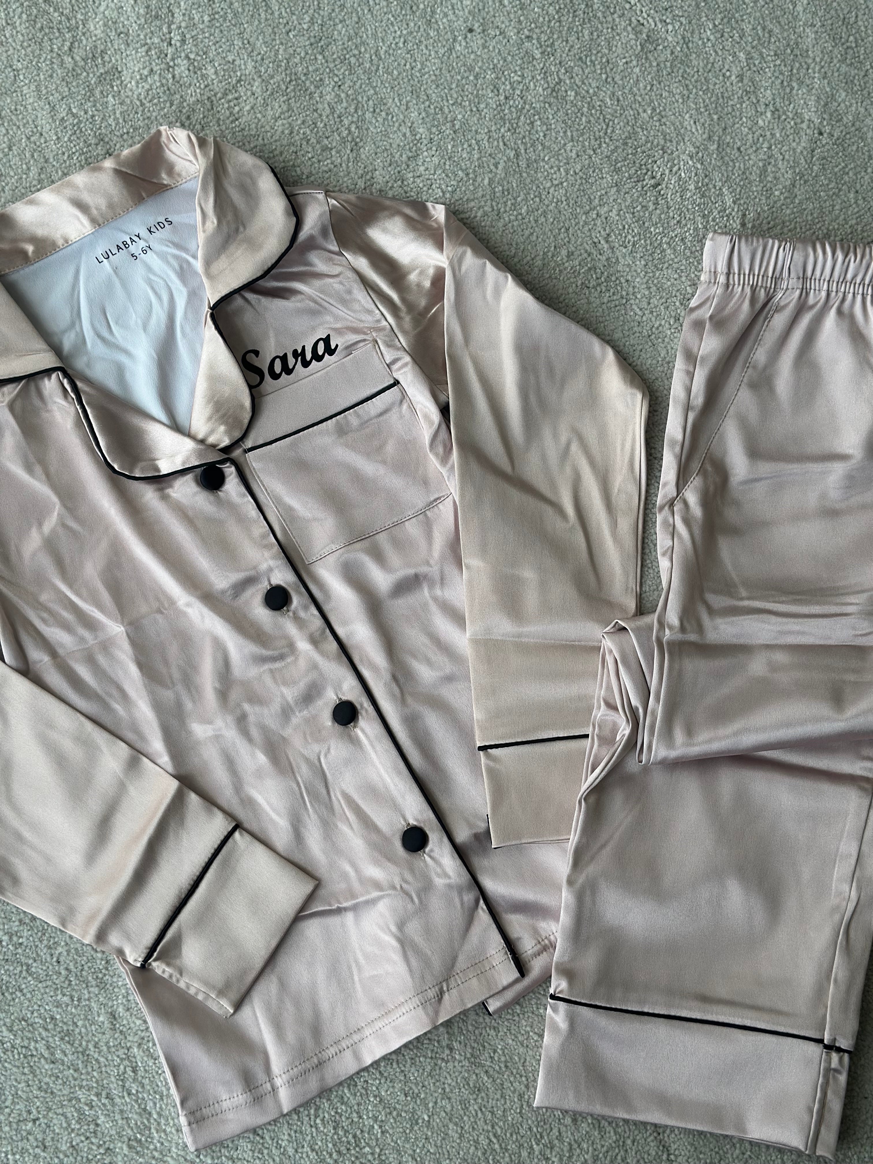 These include a button up shirt with your personalised name above the pocket and trousers, with pockets on either side and an adjustable tie around the waist. The perfect personalised gift for children! Champagne body colour with a Black contrast piping and buttons. Personalised for you! 