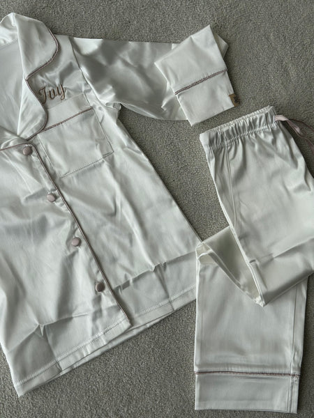 These include a button up shirt with your personalised name above the pocket and trousers, with pockets on either side and an adjustable tie around the waist. The perfect personalised gift for children! Ivory body colour with a Champagne contrast piping and buttons. Personalised for you! 
