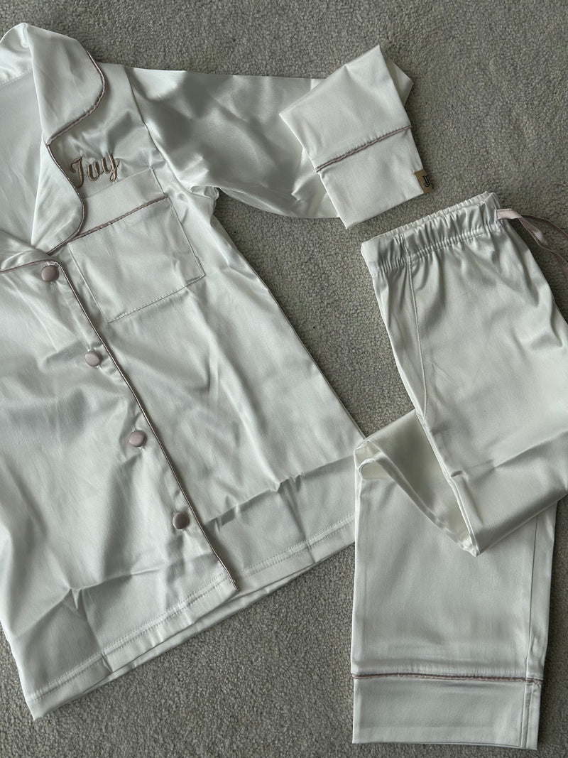 These include a button up shirt with your personalised name above the pocket and trousers, with pockets on either side and an adjustable tie around the waist. The perfect personalised gift for children! Ivory body colour with a Champagne contrast piping and buttons. Personalised for you! 