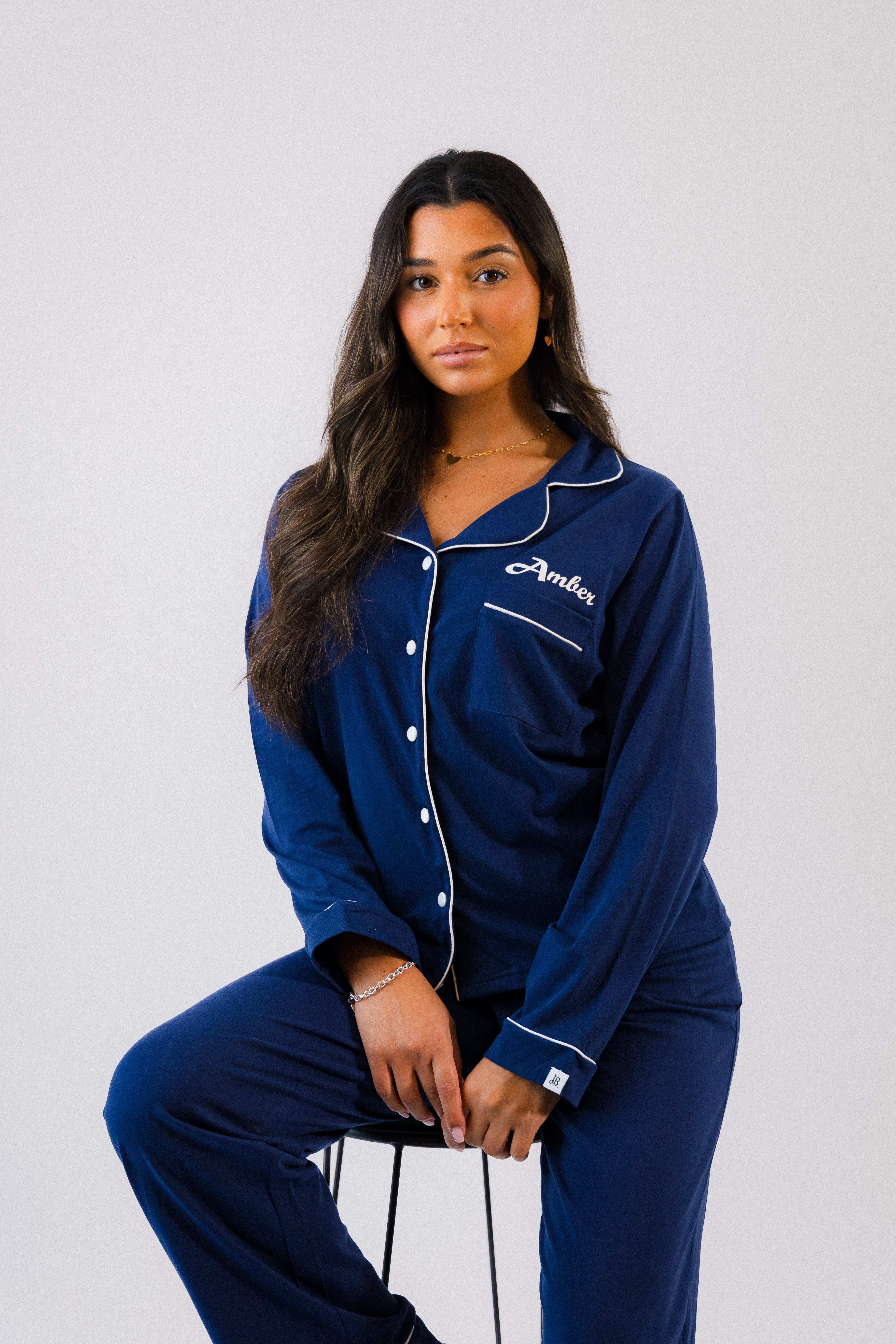 A beautiful set of ladies personalised blue jersey pyjamas. Soft and comfortable personalisation above the front pocket on the left chest . White contrasting trim around the collar alongside the buttons down to the front, also around the ankles and wrist . A nice classy design with your comfort in mind. 