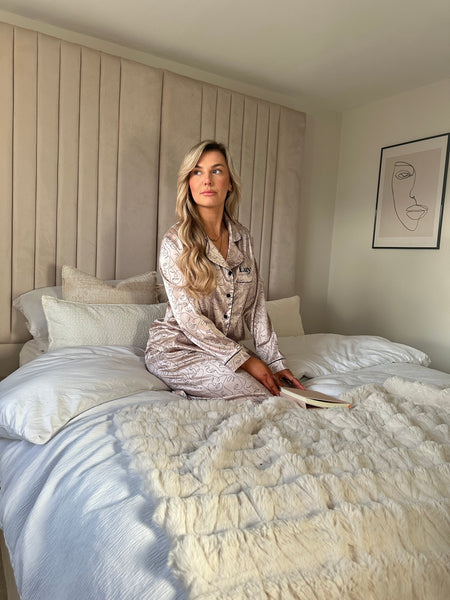 Ladies personalised satin pyjamas featuring a long sleeve shirt, button up design and pocket to the right of the shirt with personalisation above the pocket. Matched with trousers with pockets on either side and adjustable drawcord around the waist. Both the shirt and trouser in this pyjama set is sold as a set together, with a luxurious abstract face design all over and contrast piping. 