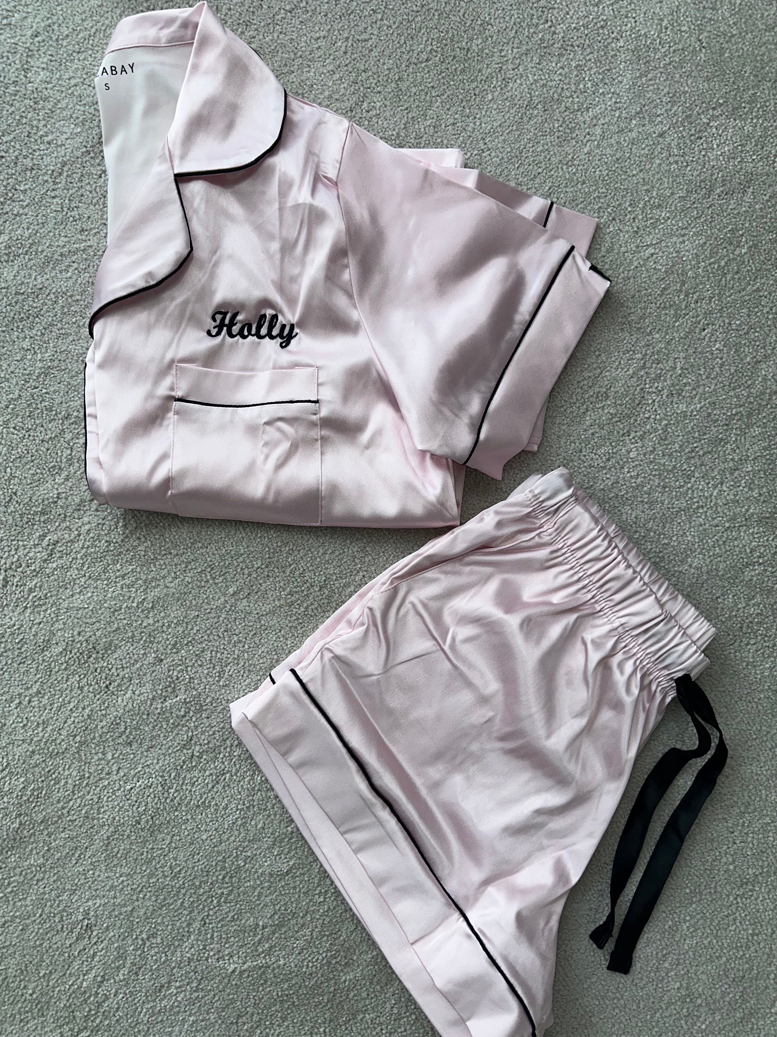 Ladies light pink satin pyjamas. Button up shirt with your personalised name above the pocket with matching shorts. Body colour light pink with a black contrast piping and buttons. Personalised for you! 