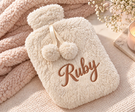 Personalised hot water bottle in a cream colour. Created from a premium borg fabric with a name embroidered on the front cover of the hot water botttle and a rubber insert of 2L inside. 